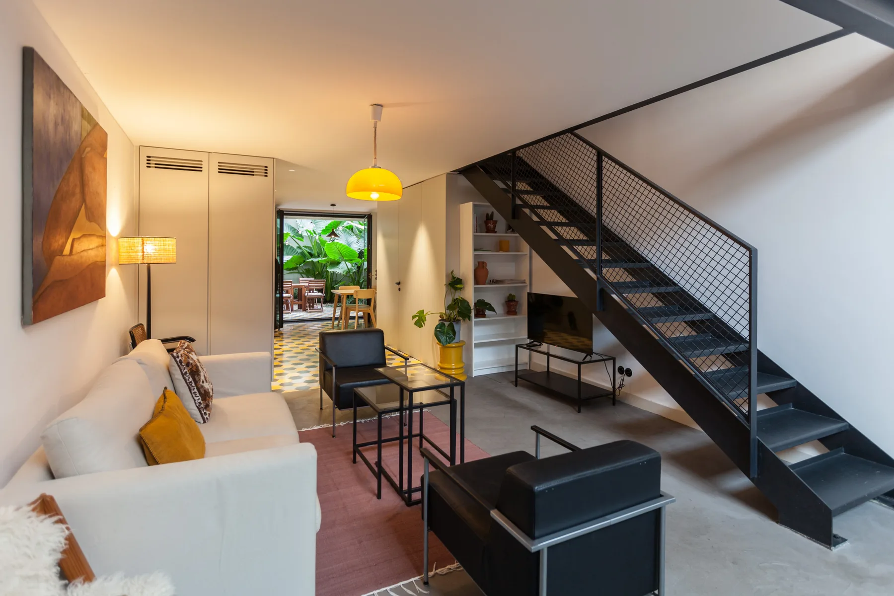 Sala de estar con asientos, una mesa de centro y una escalera a un nivel superior.
