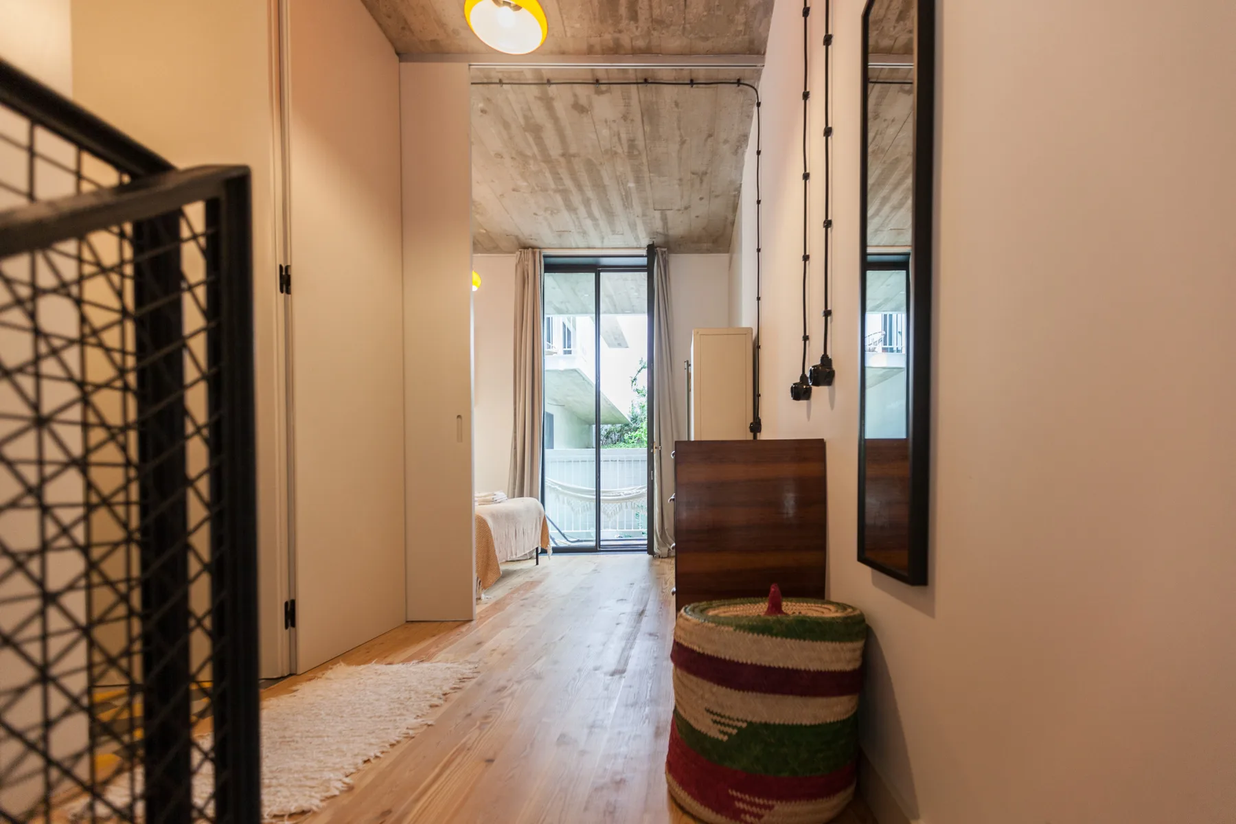 Pasillo interior con suelo de madera que conduce a una sala luminosa.