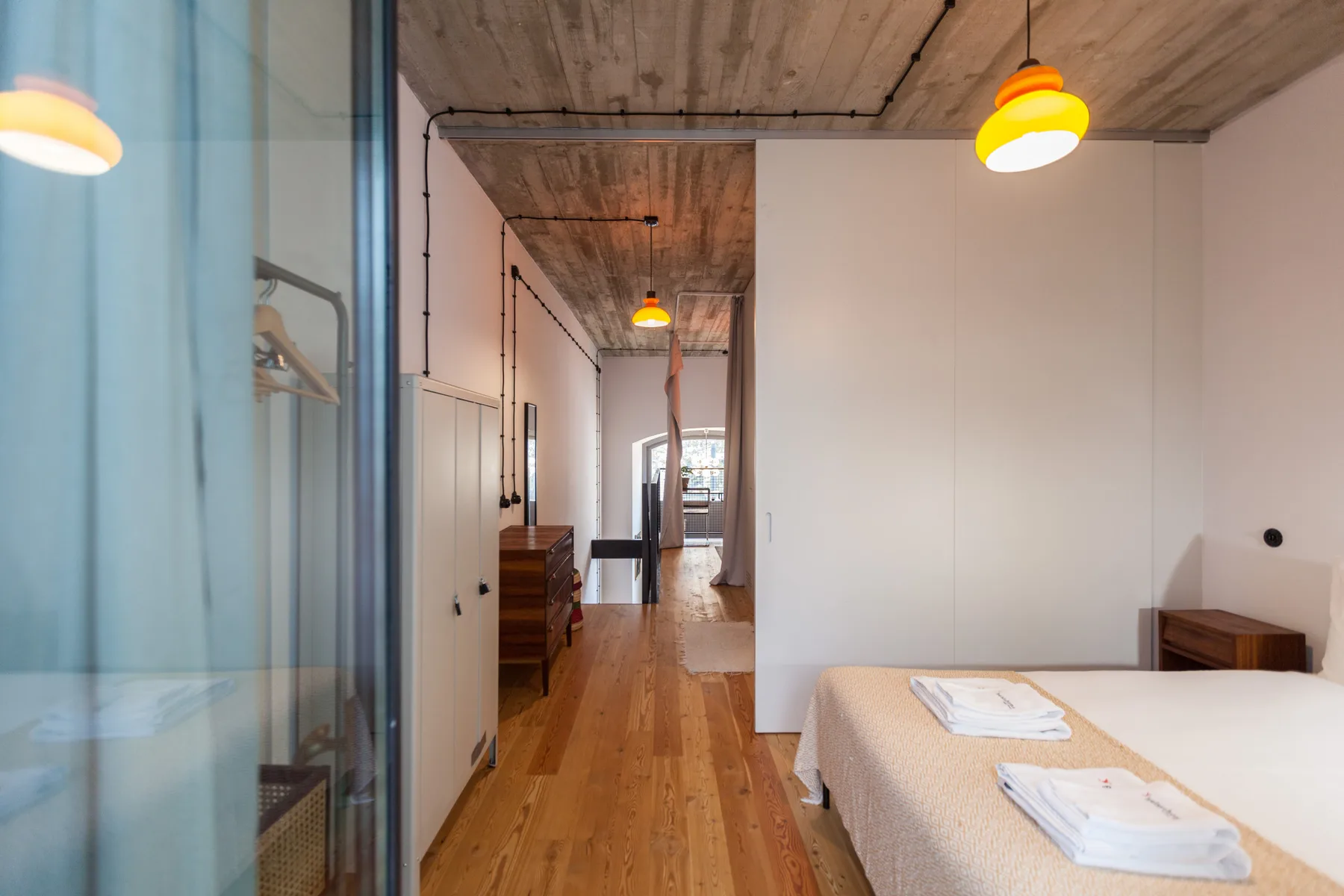 Dormitorio con una cama junto a un pasillo estrecho y techo de madera.