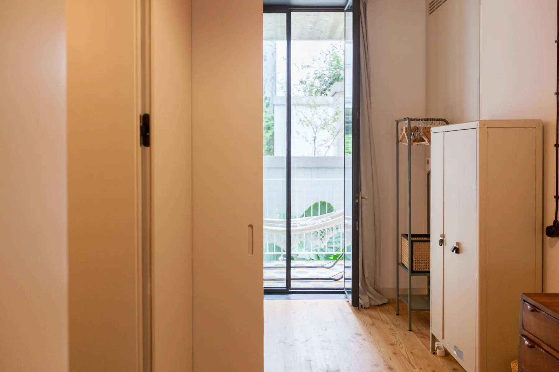 Una zona de dormitorio da a un balcón luminoso a través de una puerta de cristal.