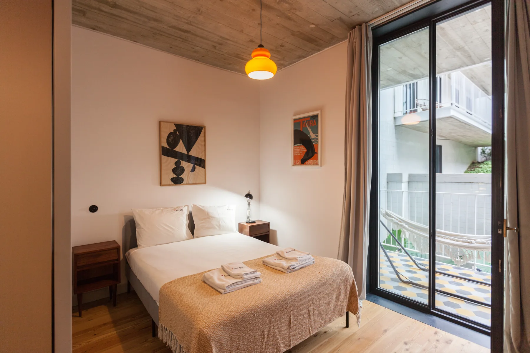 Un dormitorio con una cama doble junto a una gran puerta de cristal.