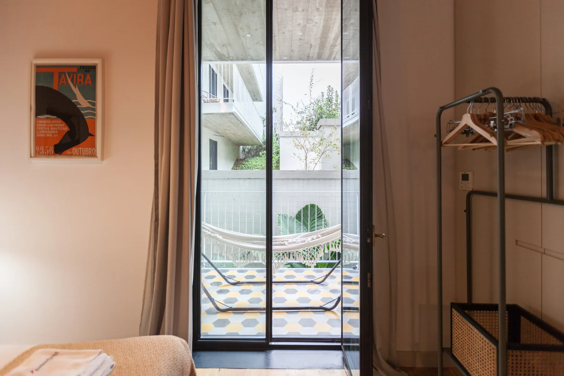 Un dormitorio da a un patio interior con una hamaca y suelo estampado.