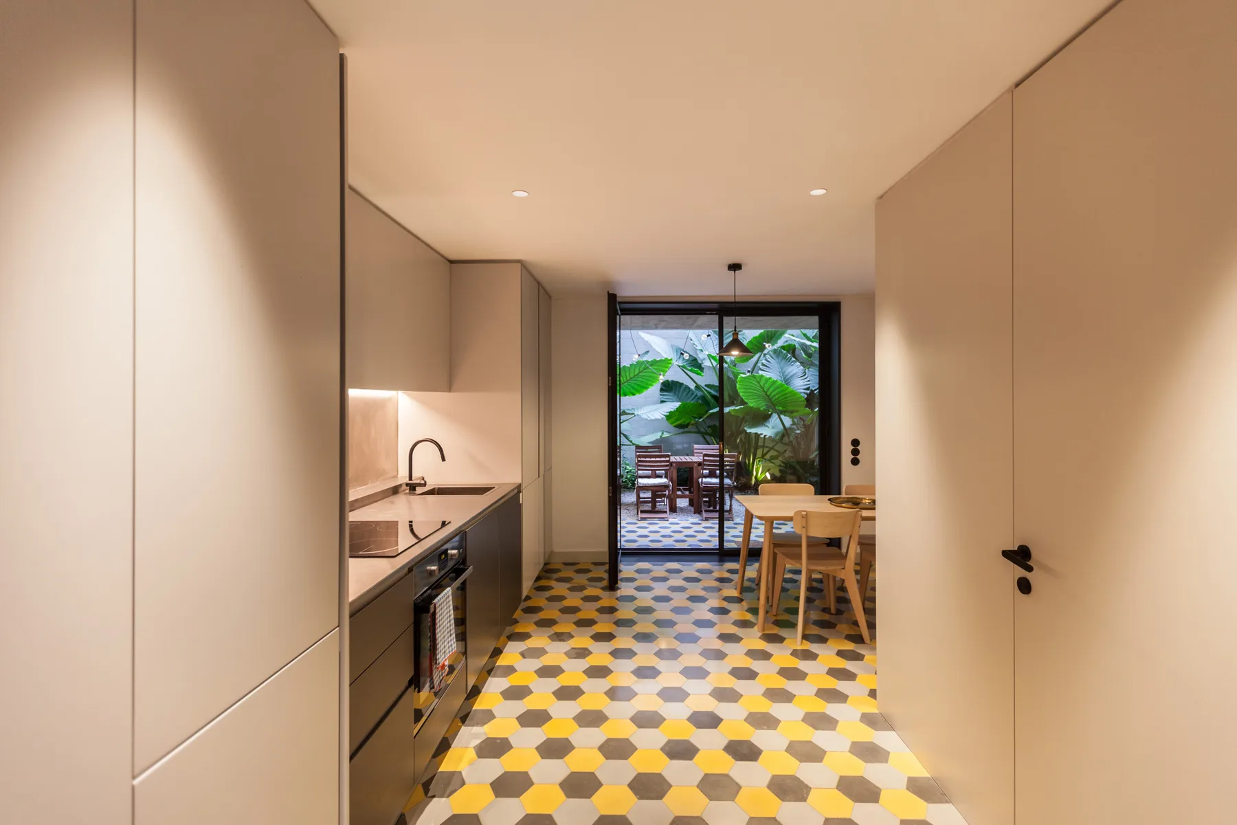 Una cocina moderna se abre a un comedor y a un patio frondoso.