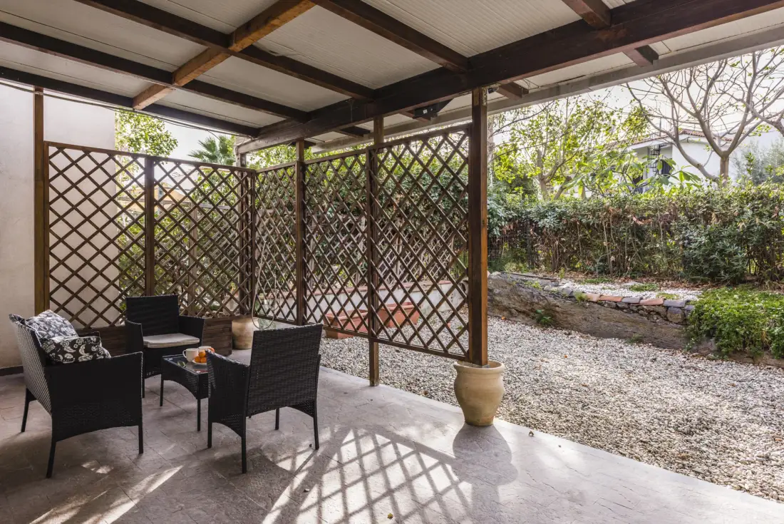 Un patio cubierto con asientos oscuros da a un jardín de grava.