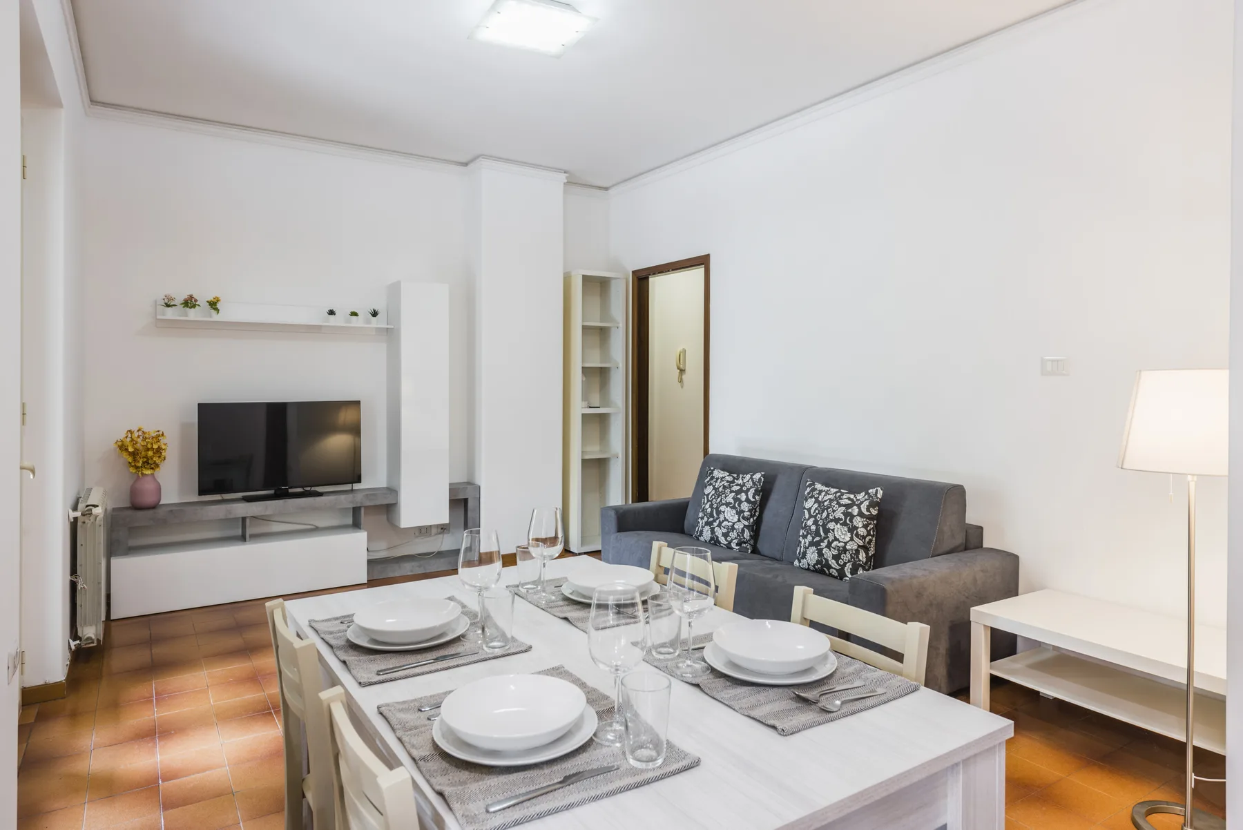 Sala de estar con televisor, asientos y una mesa de comedor.