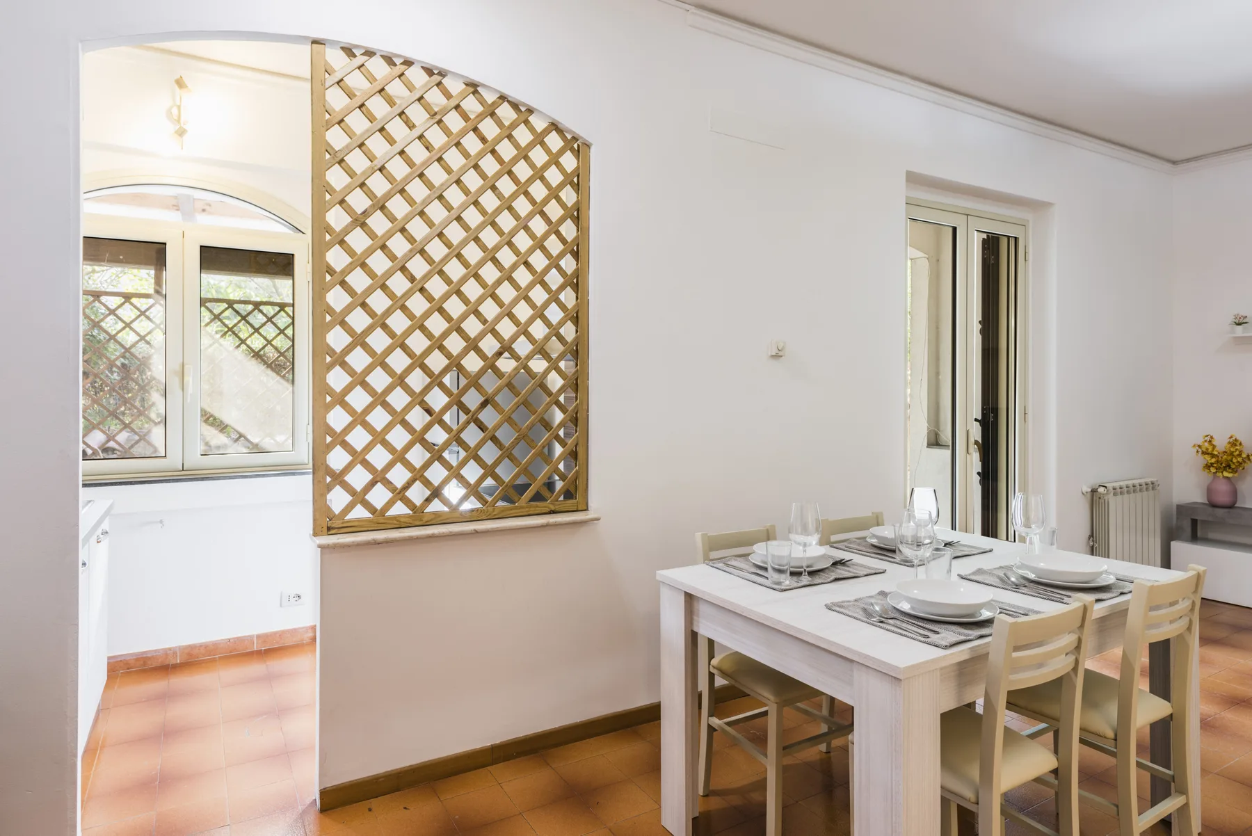 Un comedor con la mesa puesta junto a una celosía de madera.