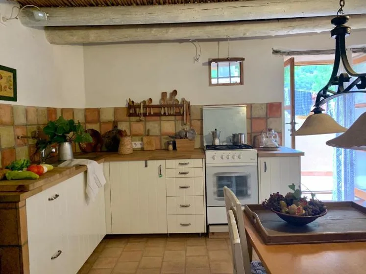 Una cocina rústica con salpicadero de azulejos, armarios blancos y una mesa de comedor.