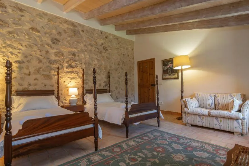 Un dormitorio con dos camas, una alfombra estampada y una zona de descanso.
