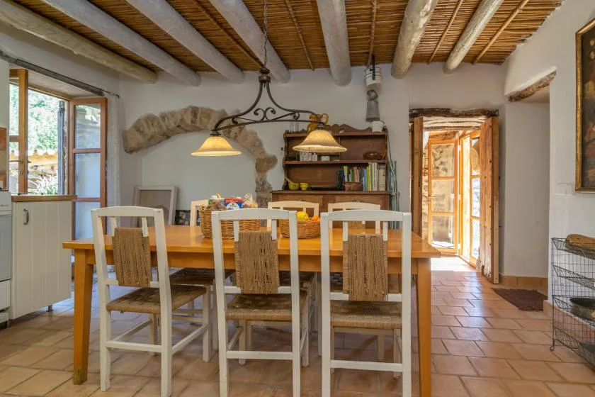 Comedor con una mesa de madera y sillas bajo vigas de techo expuestas.