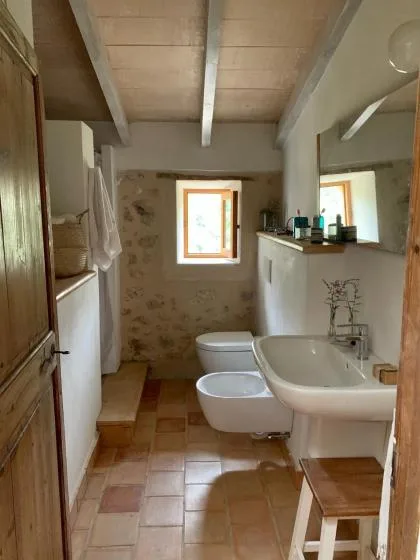 Un baño con suelo de baldosas, bañera, inodoro y una ventana pequeña.