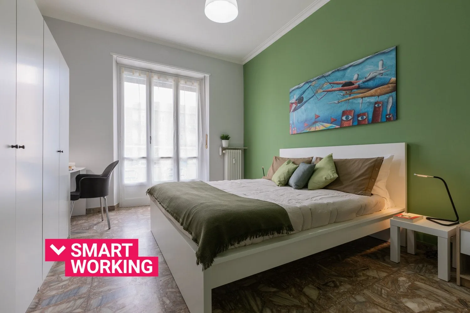 A bedroom with a bed, a window, and colorful artwork on the wall.