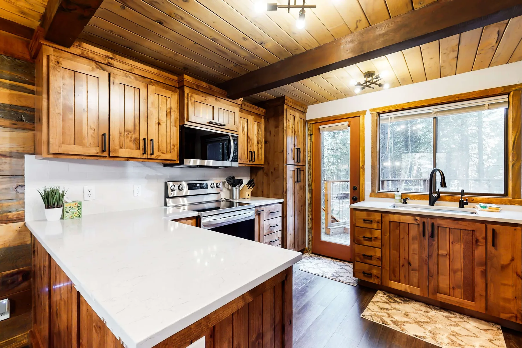 Una cocina revestida de madera con una gran isla blanca y un fregadero bajo la ventana.