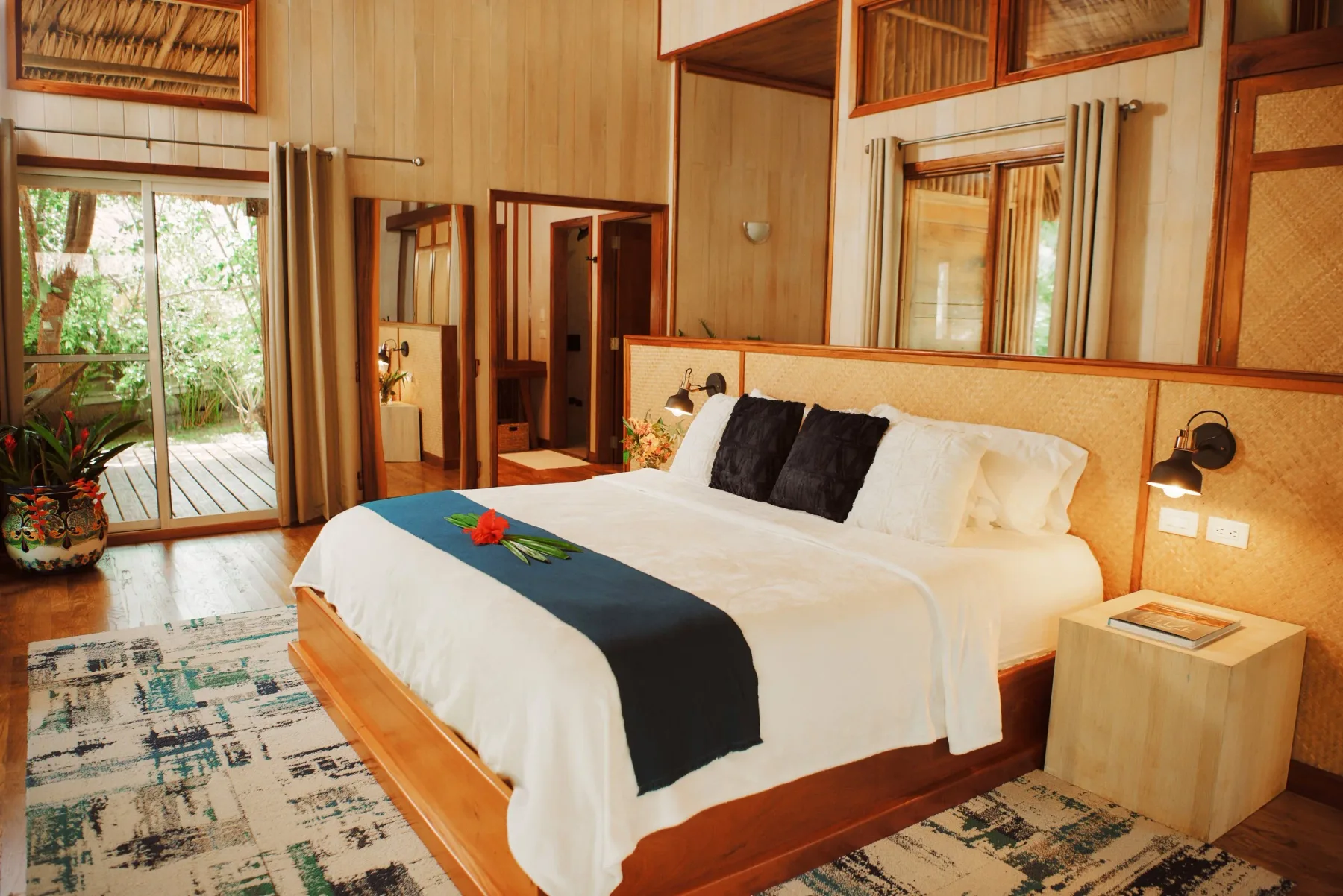 Dormitorio con una cama grande y puertas de vidrio que dan a una terraza de madera