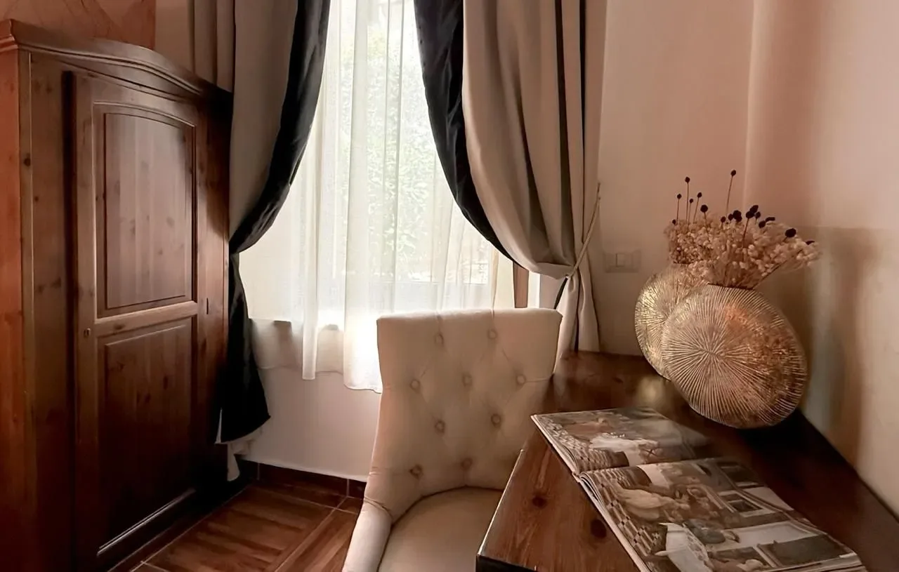 Escritorio y silla junto a una ventana con cortinas transparentes.
