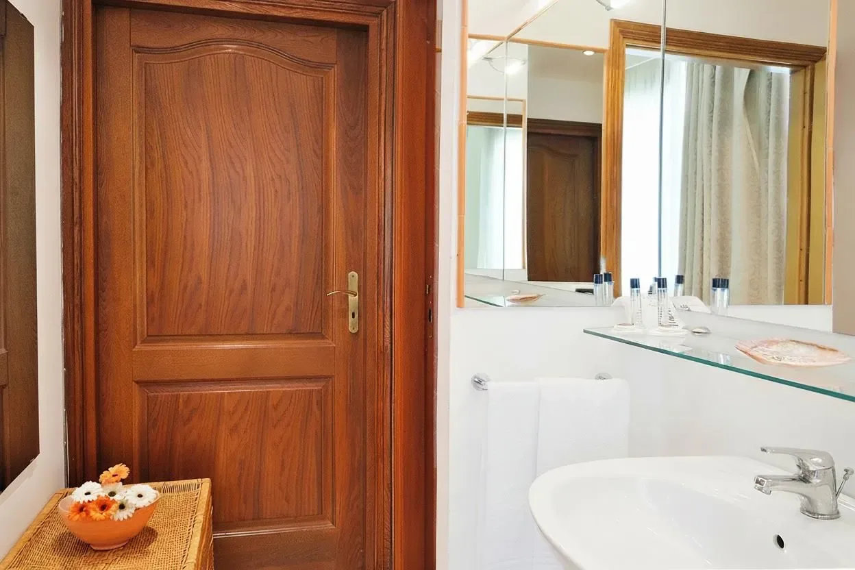 Baño con puerta de madera, lavabo y espejo.