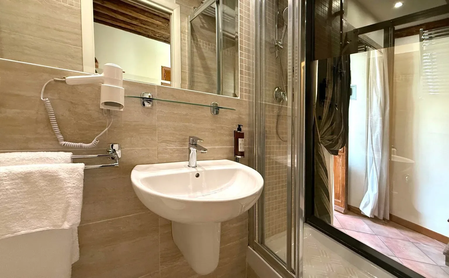 Baño con lavabo, espejo, ducha y secador de pelo.