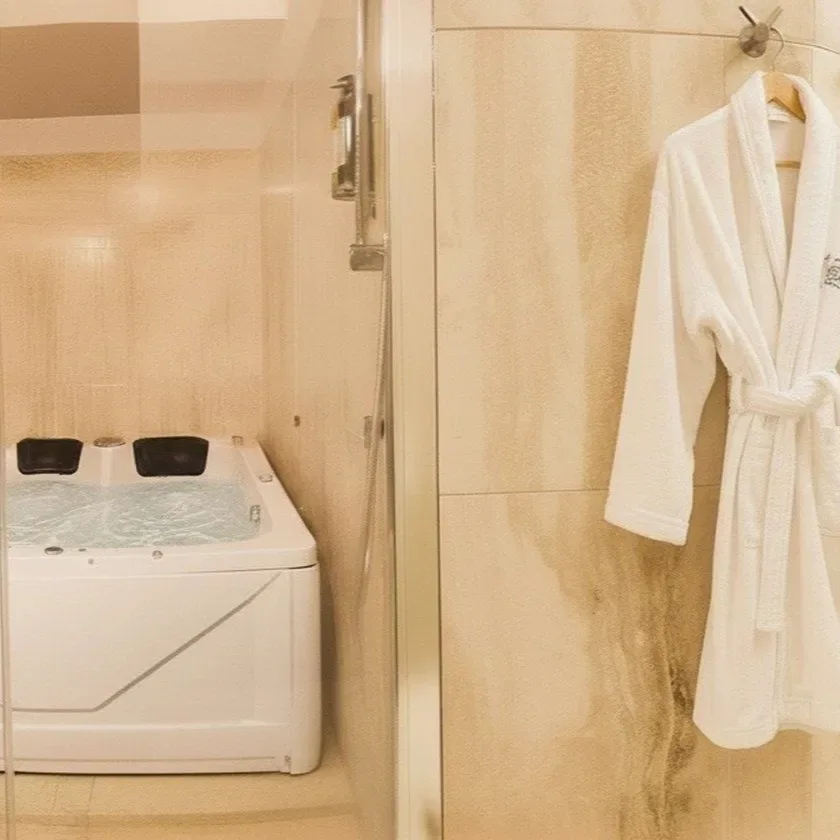 Baño con jacuzzi, ducha de cristal y albornoz.