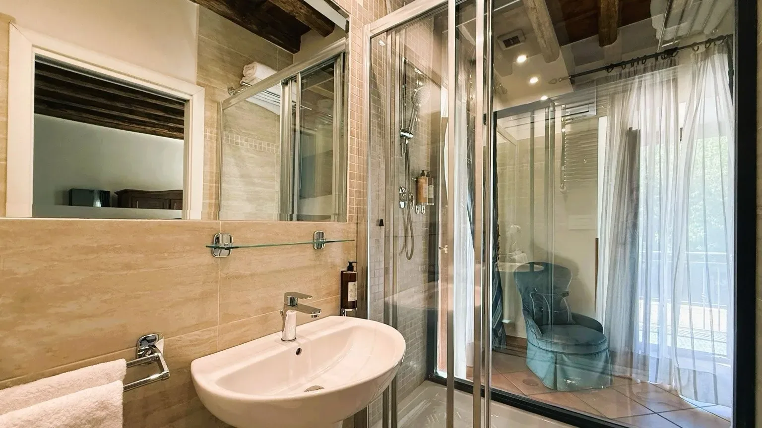 Baño con ducha de cristal, lavabo y espejo.