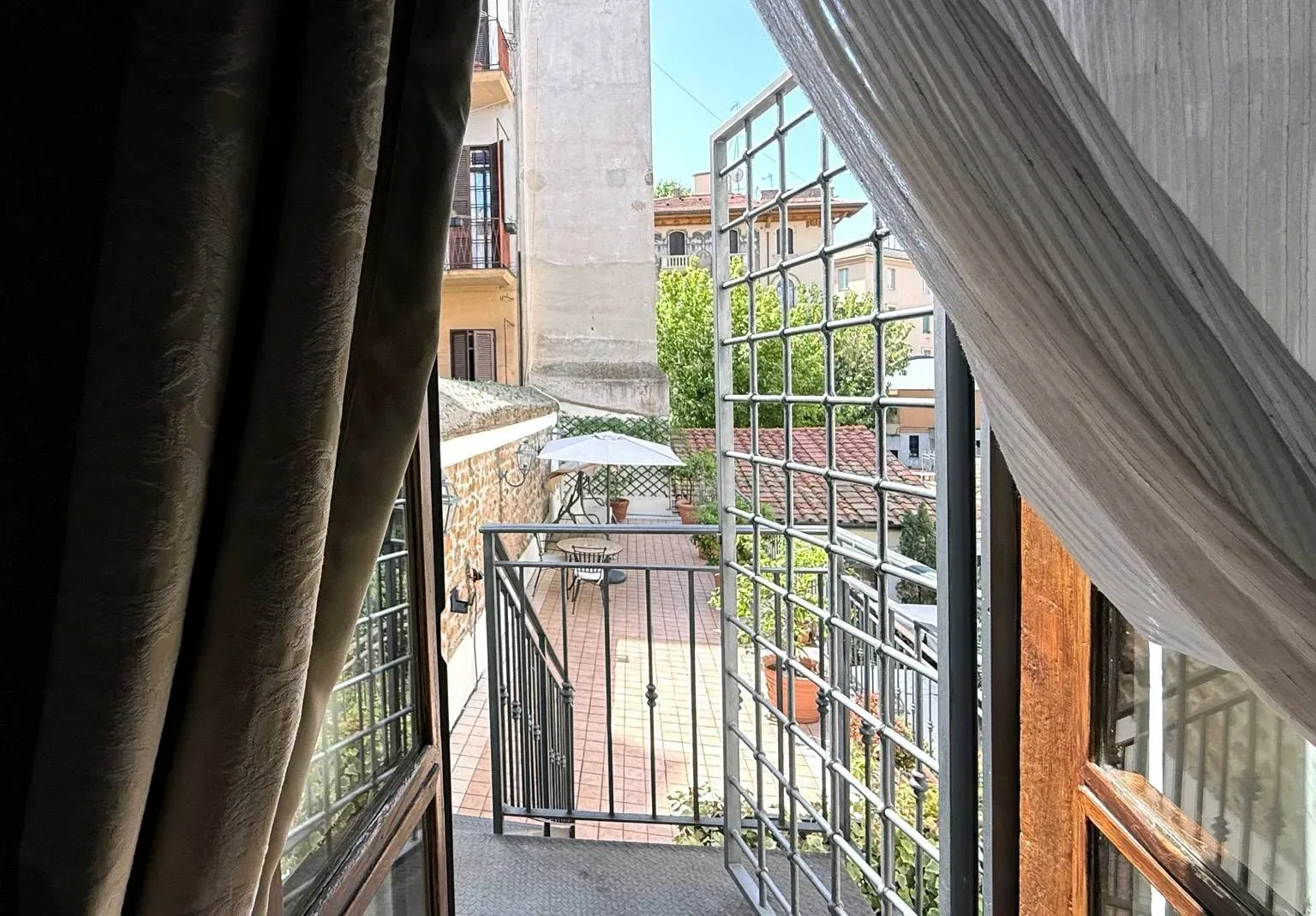 Vista a través de una ventana hacia un pequeño balcón con una puerta de hierro forjado.