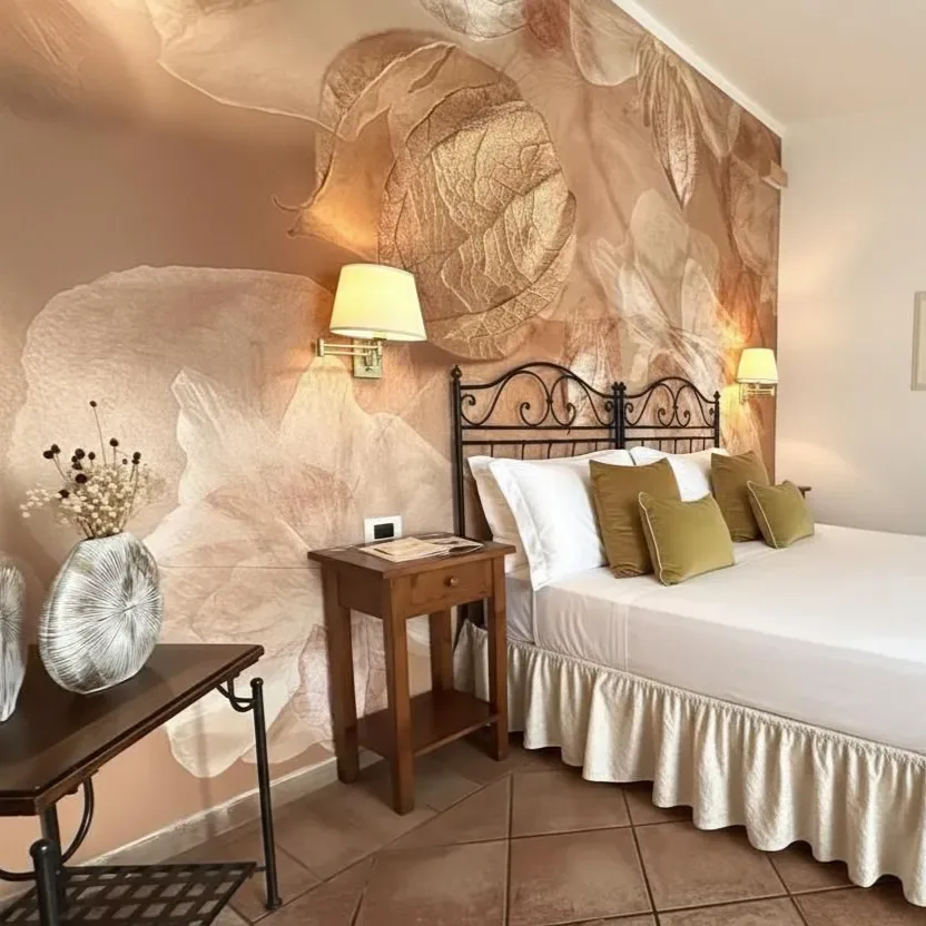 Dormitorio con mural floral, cama, mesita de noche y jarrón.