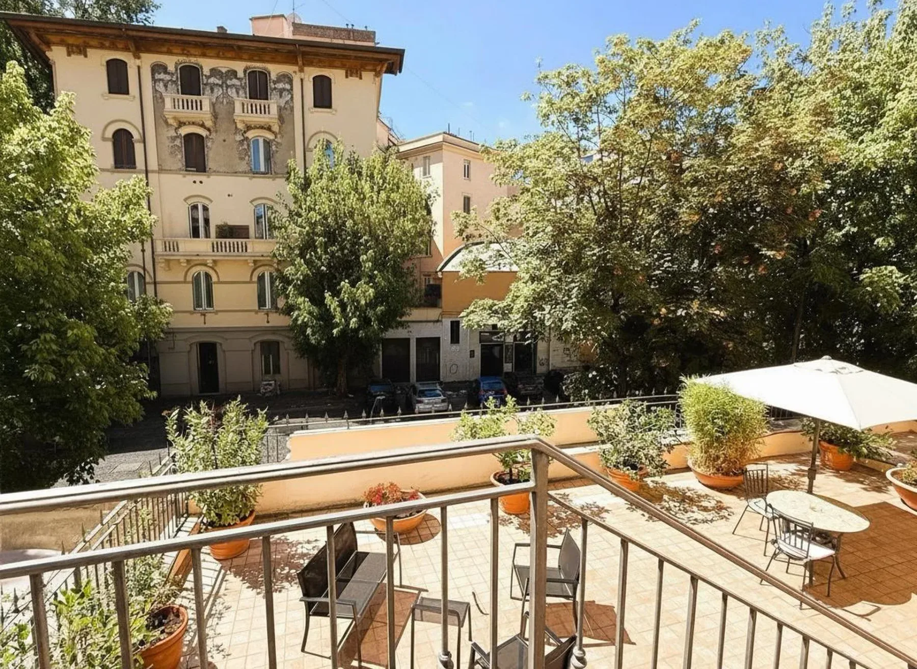 Terraza con vistas a un patio con árboles, edificios y asientos.