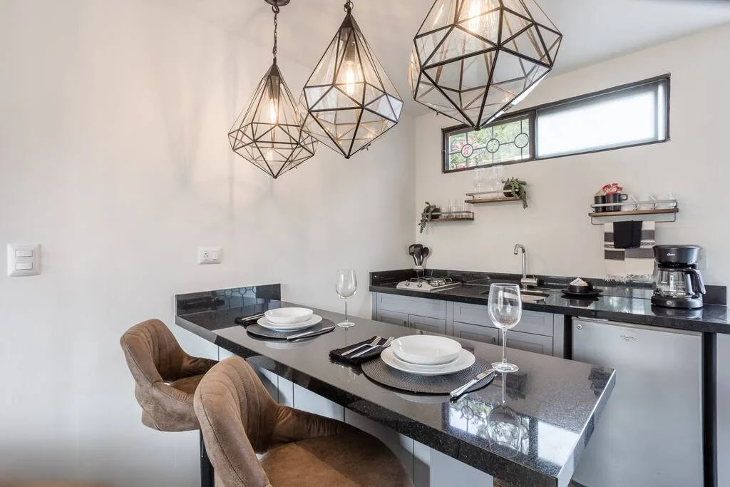 Kitchen and dining area with geometric pendant lights and black granite countertops