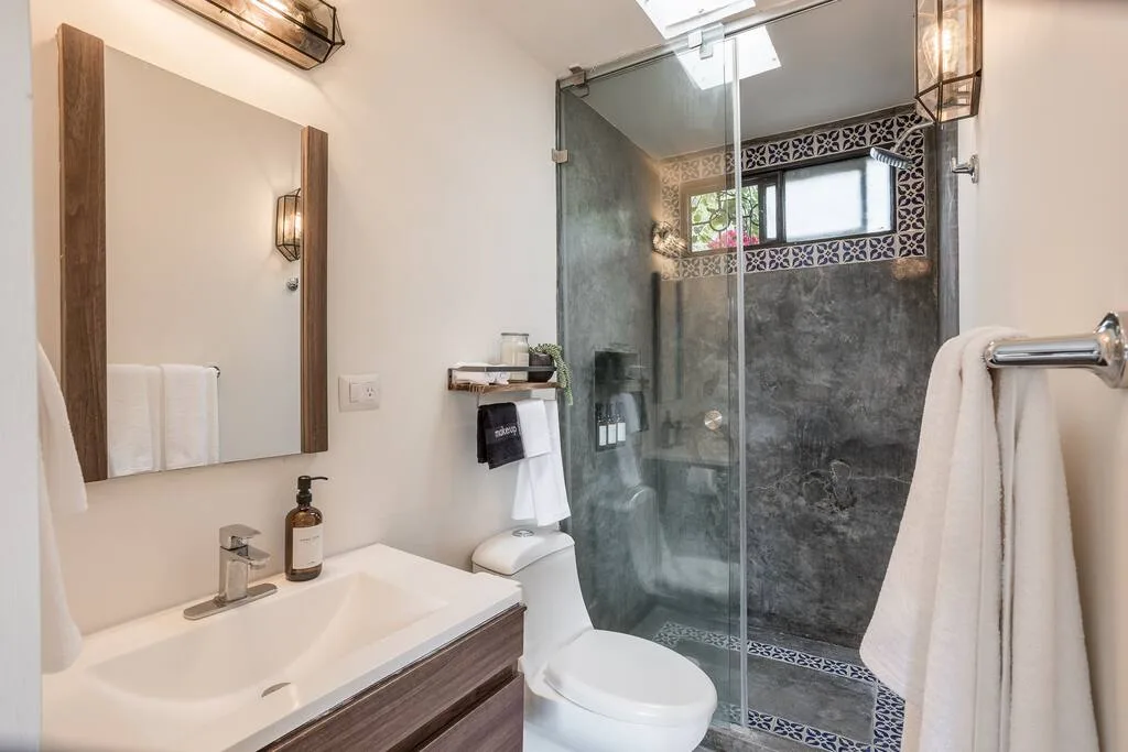 Full bathroom with walk-in shower, wooden vanity with mirror, and decorative tile accents