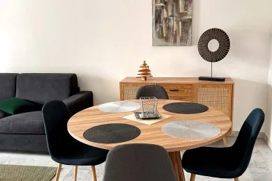 A dining area with a round wooden table, dark seating, and a sideboard.
