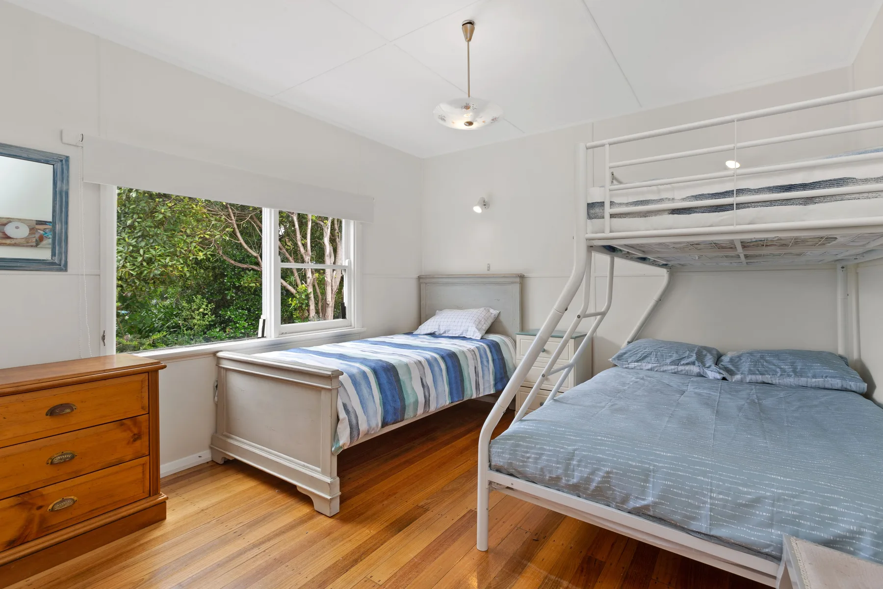 Un dormitorio luminoso con dos camas, una de ellas debajo de una litera elevada.
