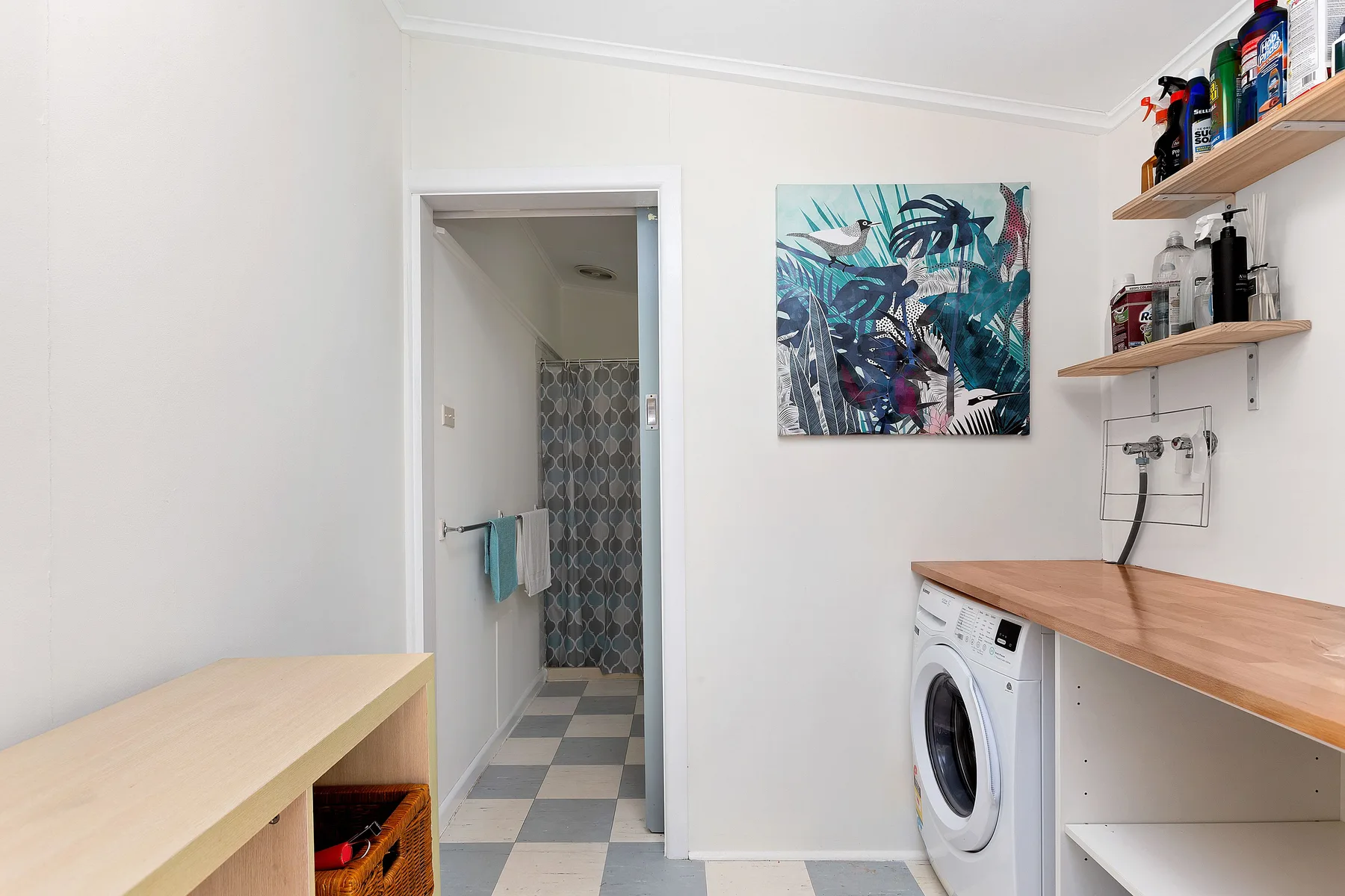 Un cuarto de lavandería con una lavadora bajo estantes de madera.
