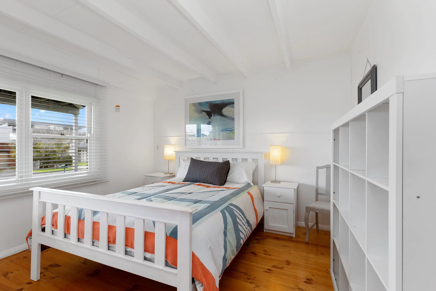 Un dormitorio luminoso con una cama, mesitas de noche y una ventana grande.