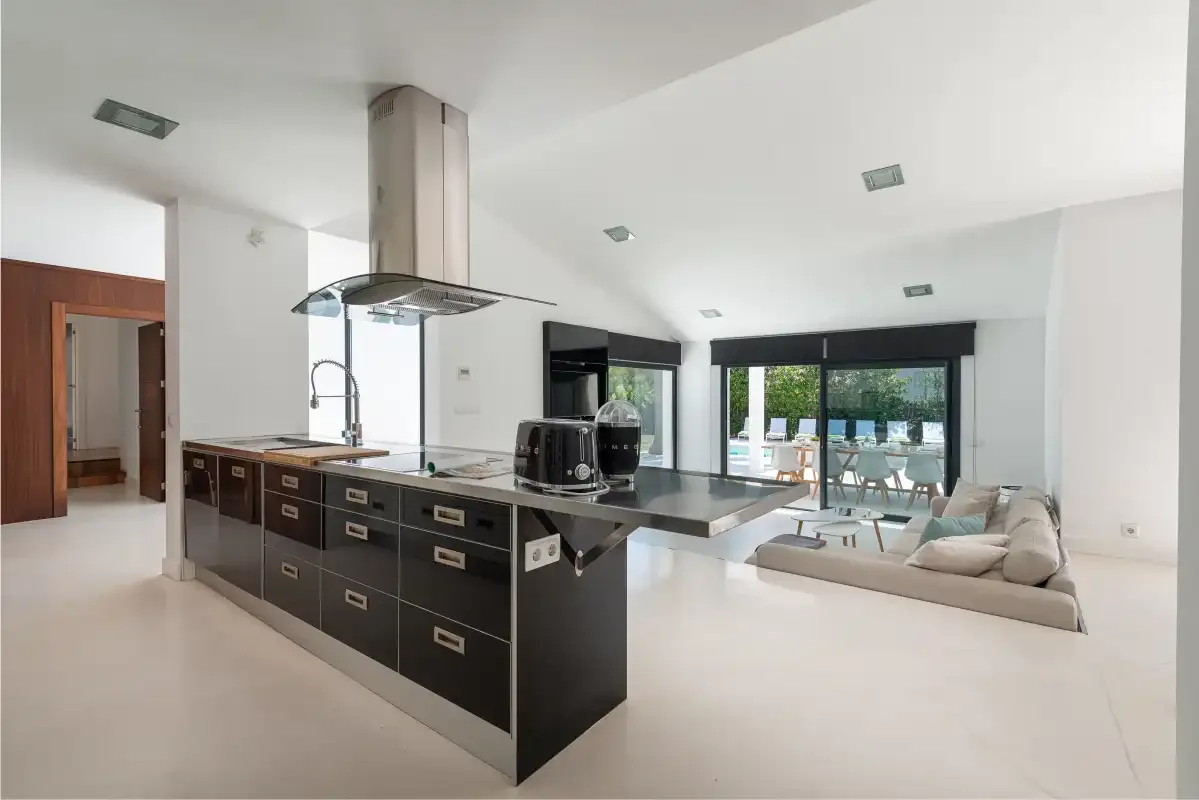 An open-plan kitchen and living area with a dining table beside the windows.