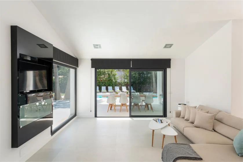 A bright living room opens onto a patio through wide glass doors.