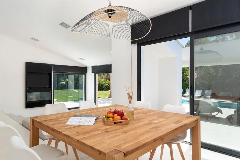 A bright dining area with a wooden table beside large glass doors.