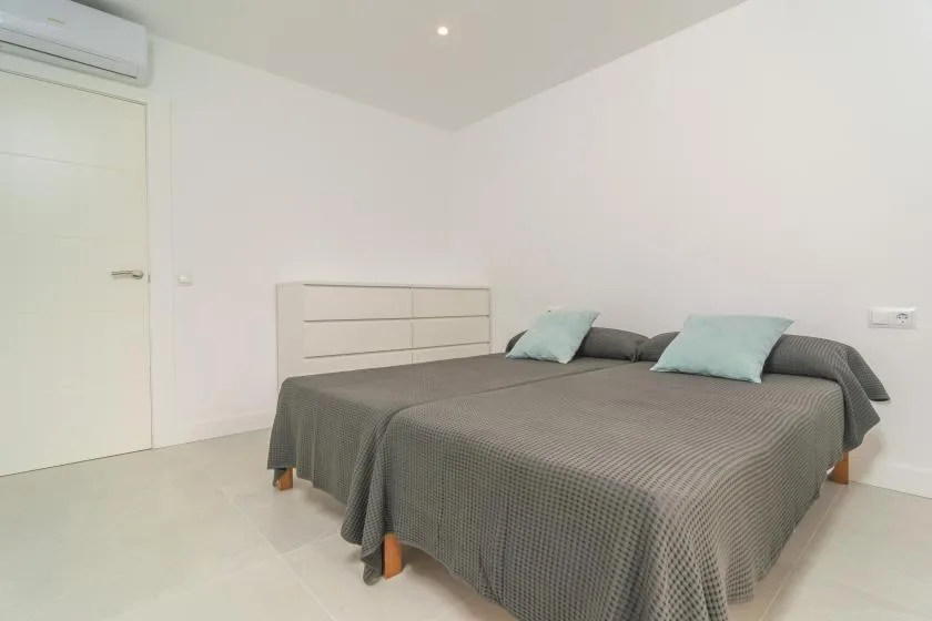 A bedroom with a double bed, gray bedspread, and pale blue pillows.