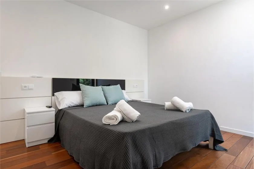 A bedroom with a large bed, pale walls, and wood flooring.