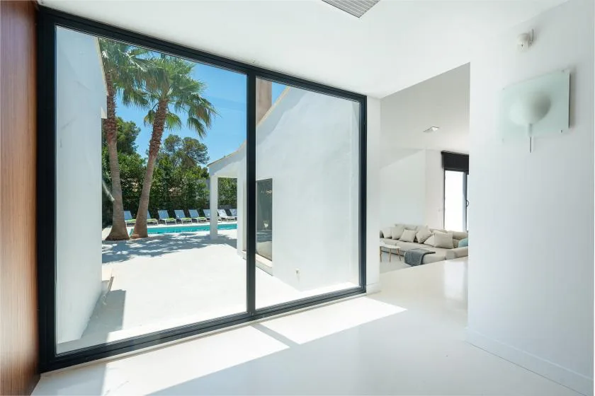 A bright interior opens through large glass doors onto a poolside patio.