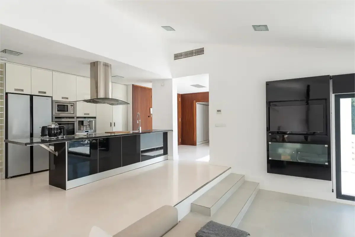 A modern kitchen opens onto a living area with a built-in television.