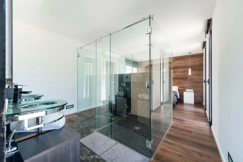 A modern bathroom with a glass shower and two sinks.