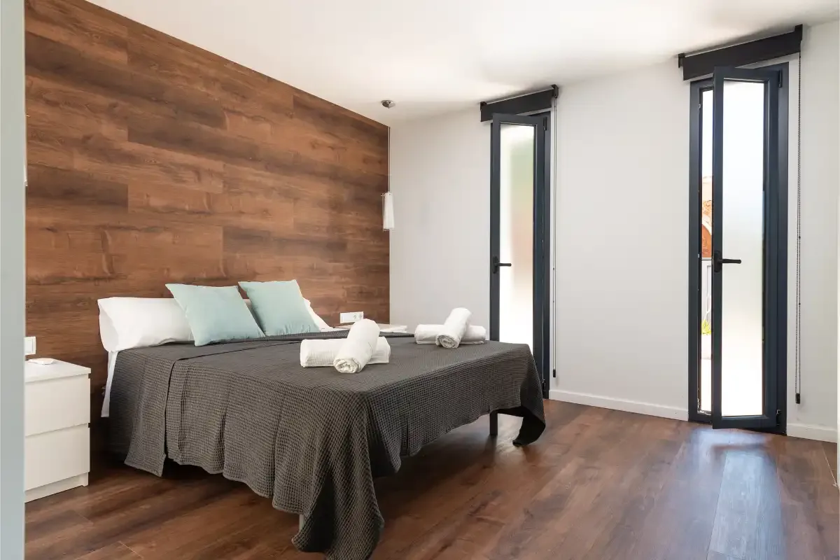 A bedroom with a bed dressed in dark bedding and pale pillows.