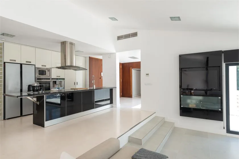 A bright open-plan kitchen and living area with a long counter and built-in television.