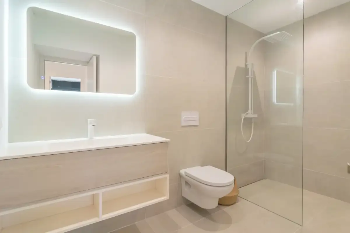 A modern bathroom with a wall-mounted sink, toilet, and glass shower.
