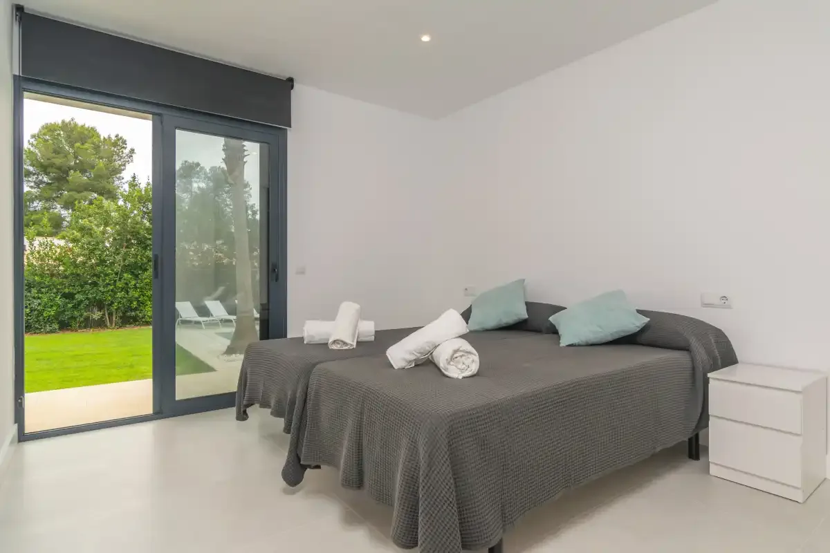 A bedroom with a bed beside sliding glass doors overlooking a garden.