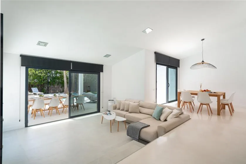 A bright living and dining area opens onto a patio through large glass doors.