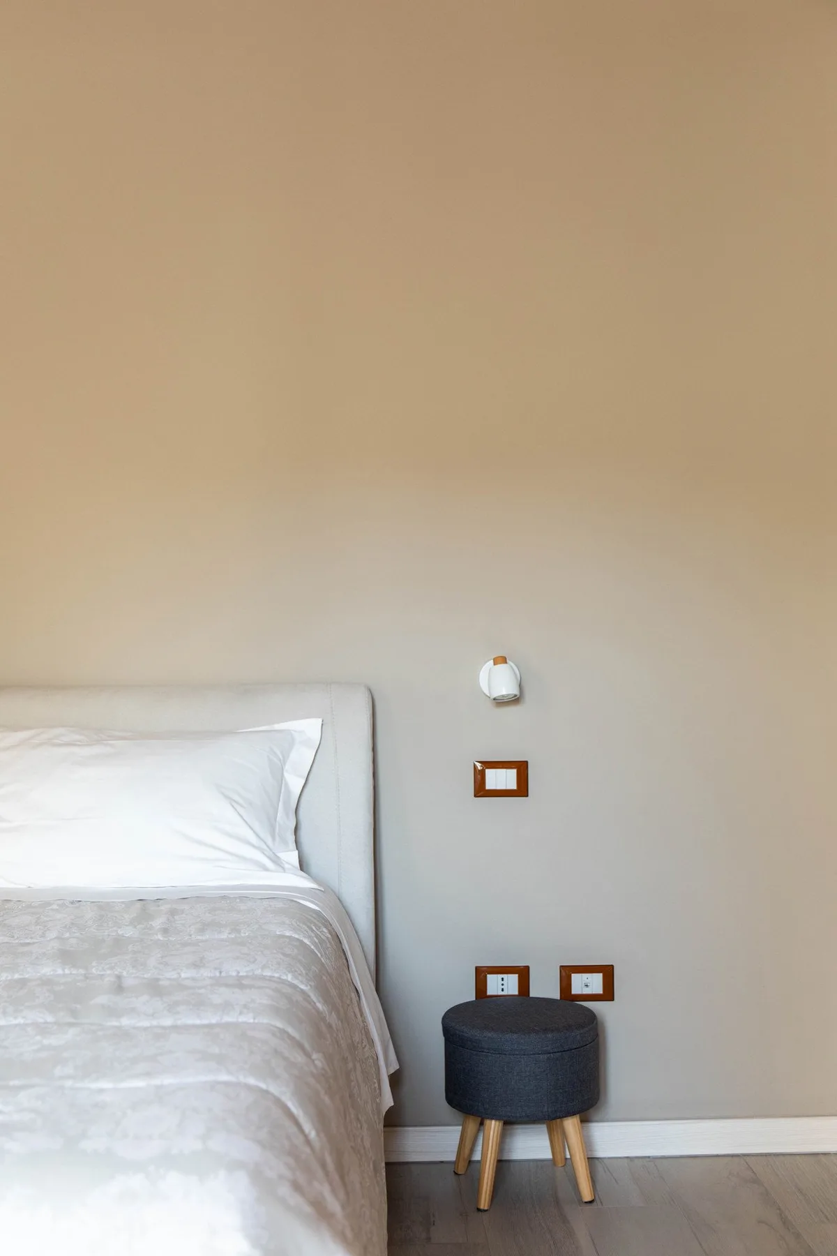Un dormitorio con una cama bien hecha y un taburete pequeño al lado.