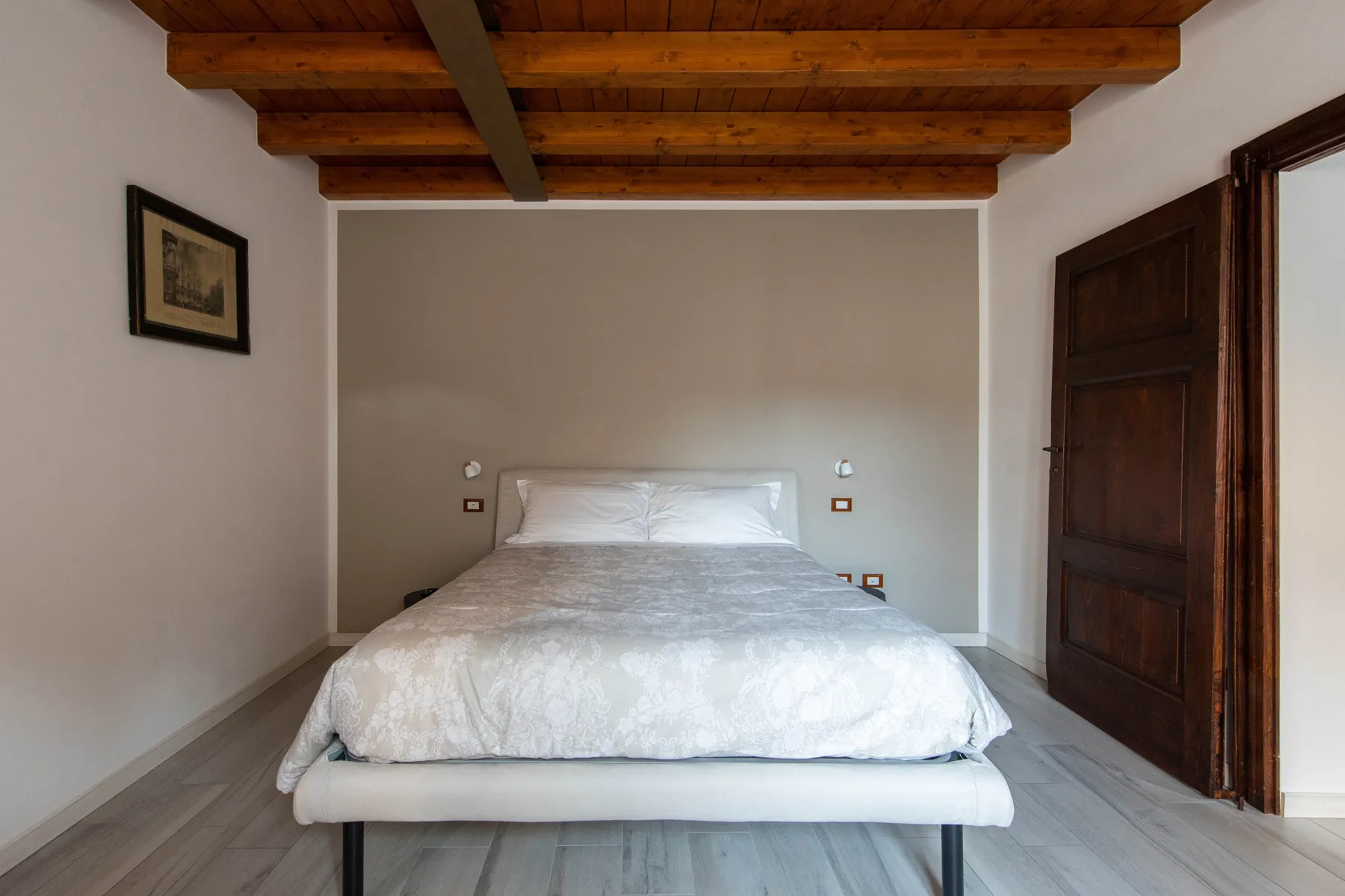 Un dormitorio con una cama bajo vigas de madera expuestas.