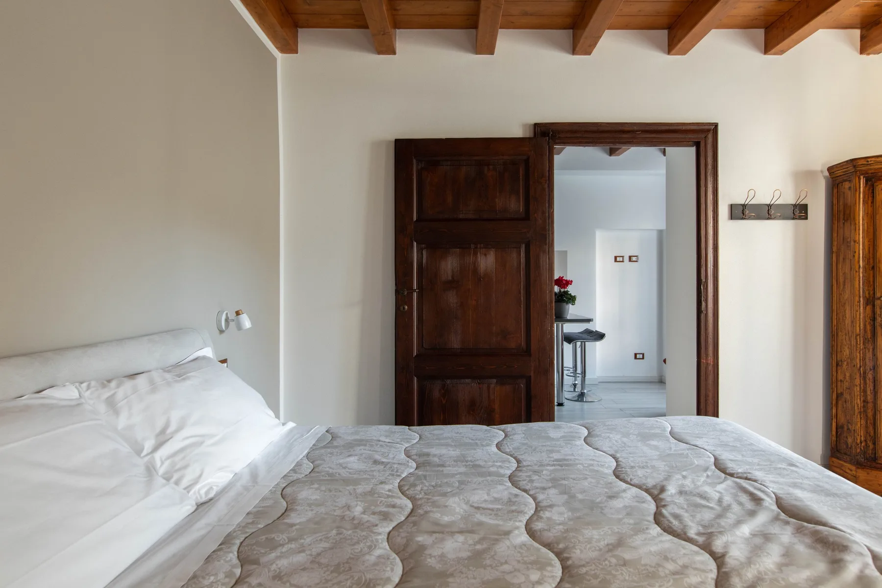 Un dormitorio con una cama bajo vigas de madera a la vista.