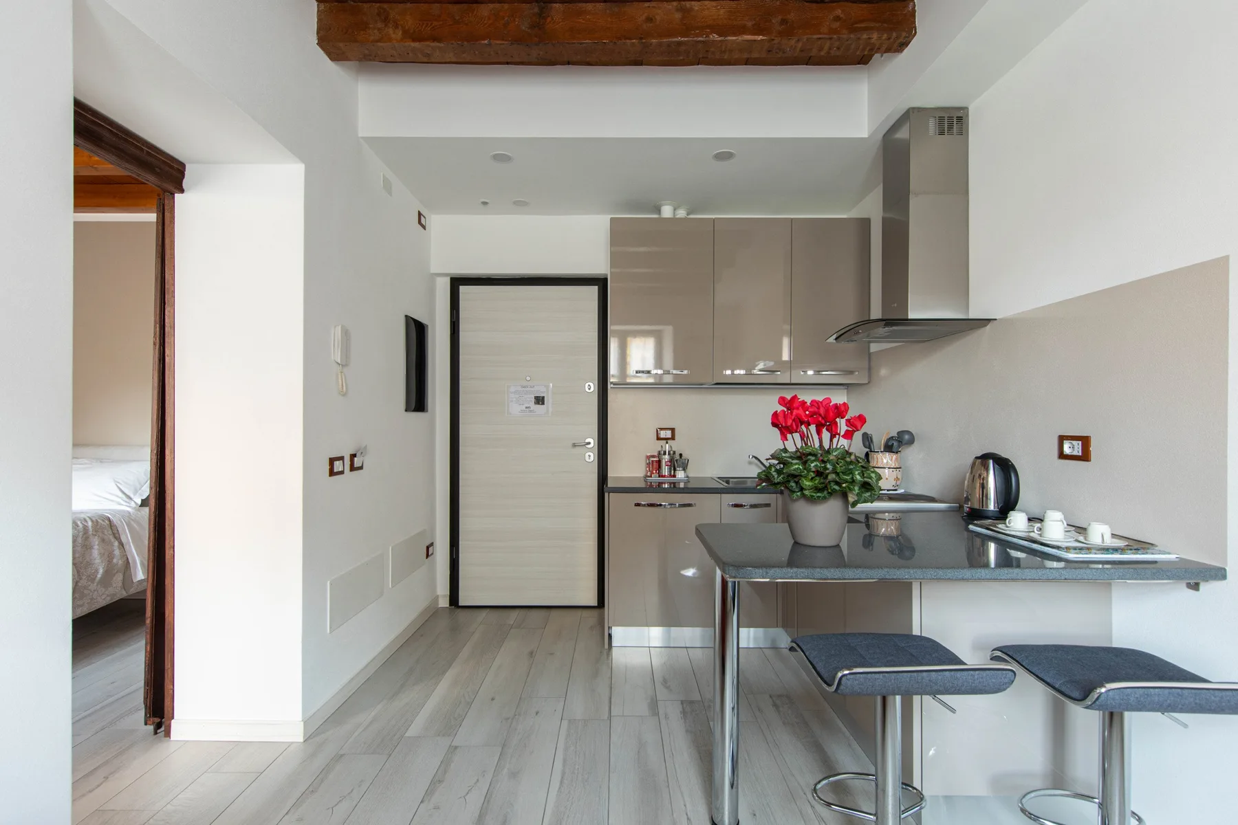 Una cocina compacta con una barra, taburetes y flores rojas.