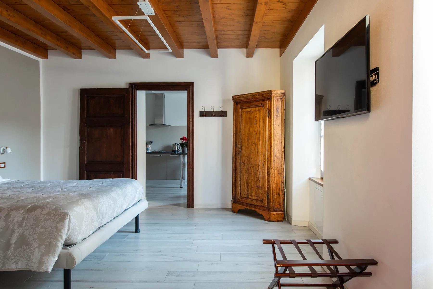 Un dormitorio con una cama, un armario de madera y un televisor en la pared.