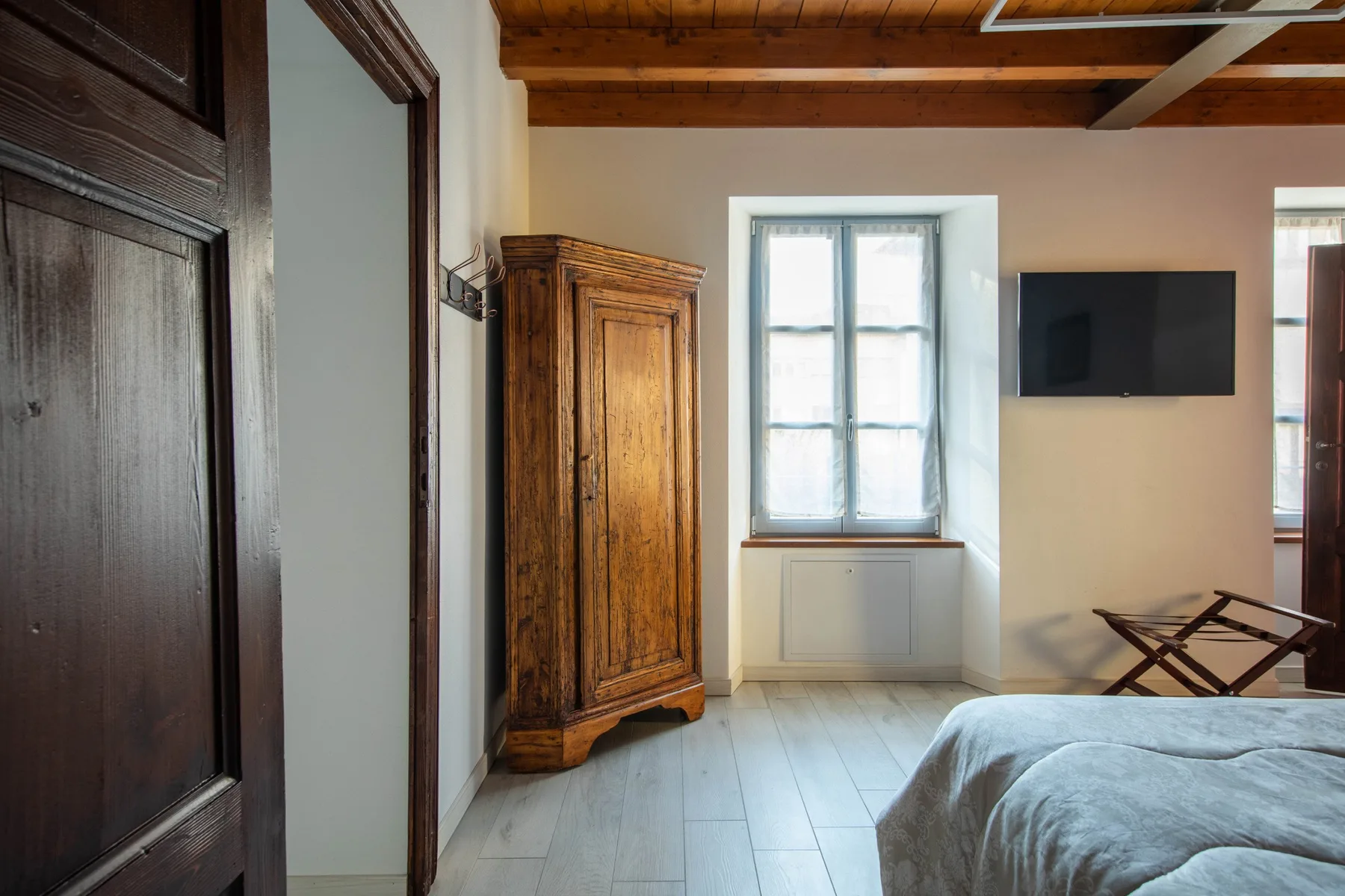 Un dormitorio con cama, armario de madera y televisor en la pared.